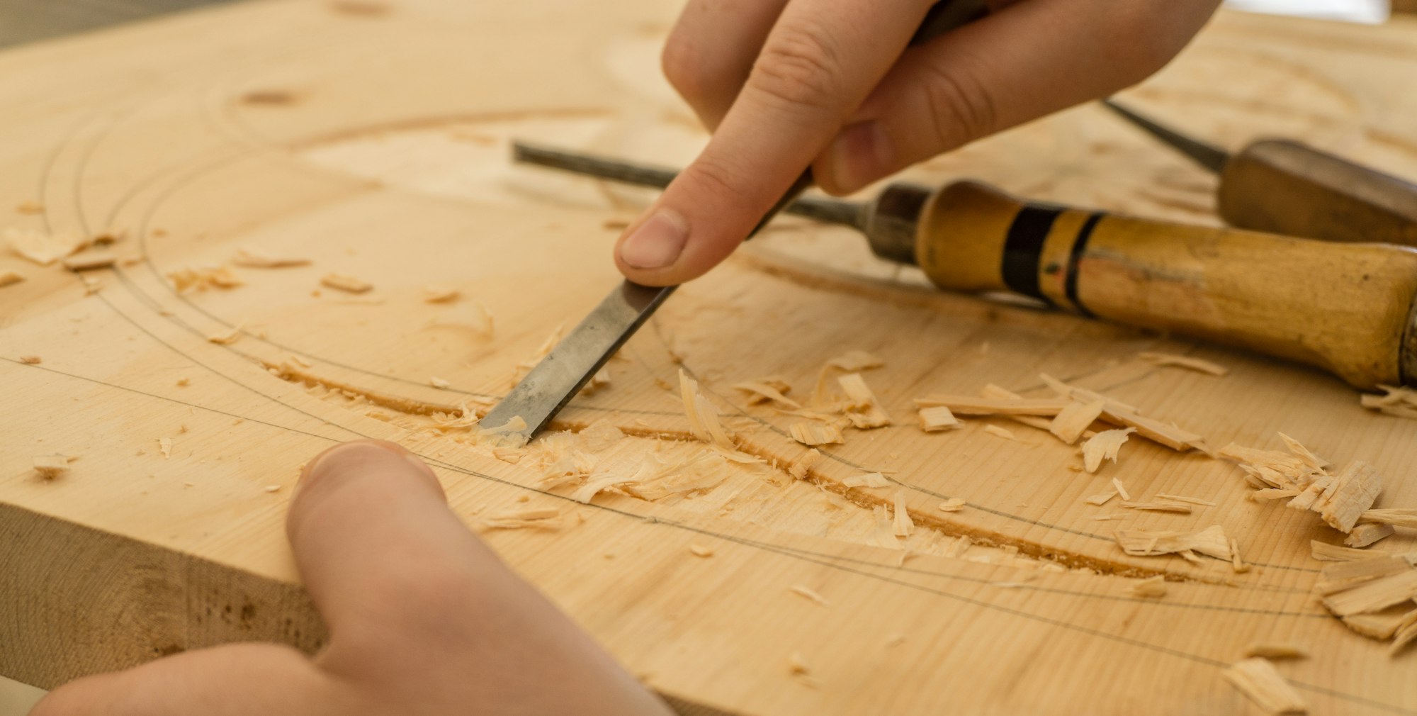 A craftsman shaping a wooden panel with a chisel